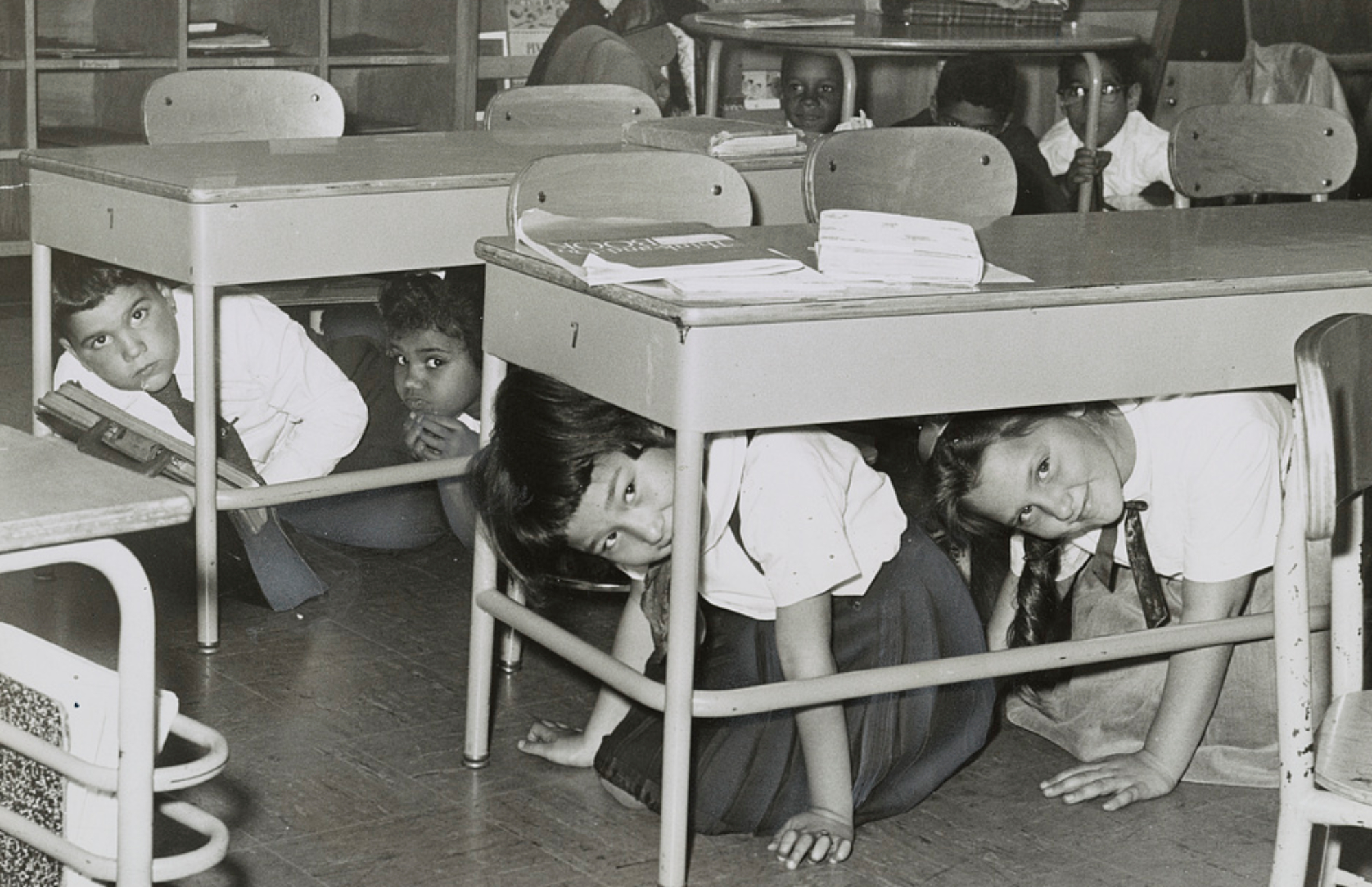 School children in a nuclear attack duck-and-cover drill in a public school in Brooklyn, New York, 1962. Photo by Walter Albertin, Library of Congress via wikimedia.