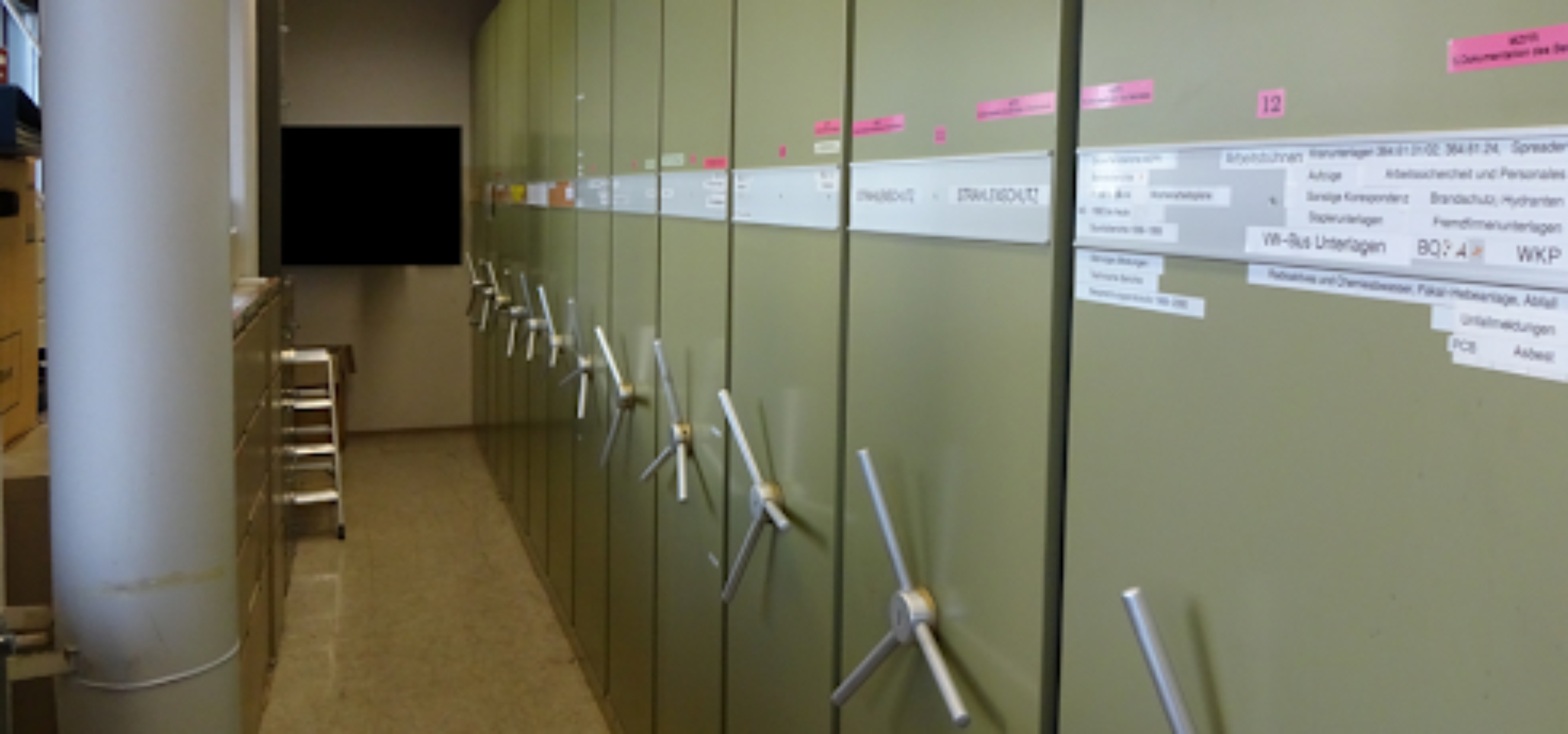 A photo of an archive library with green exterior and a tv on the far wall. 